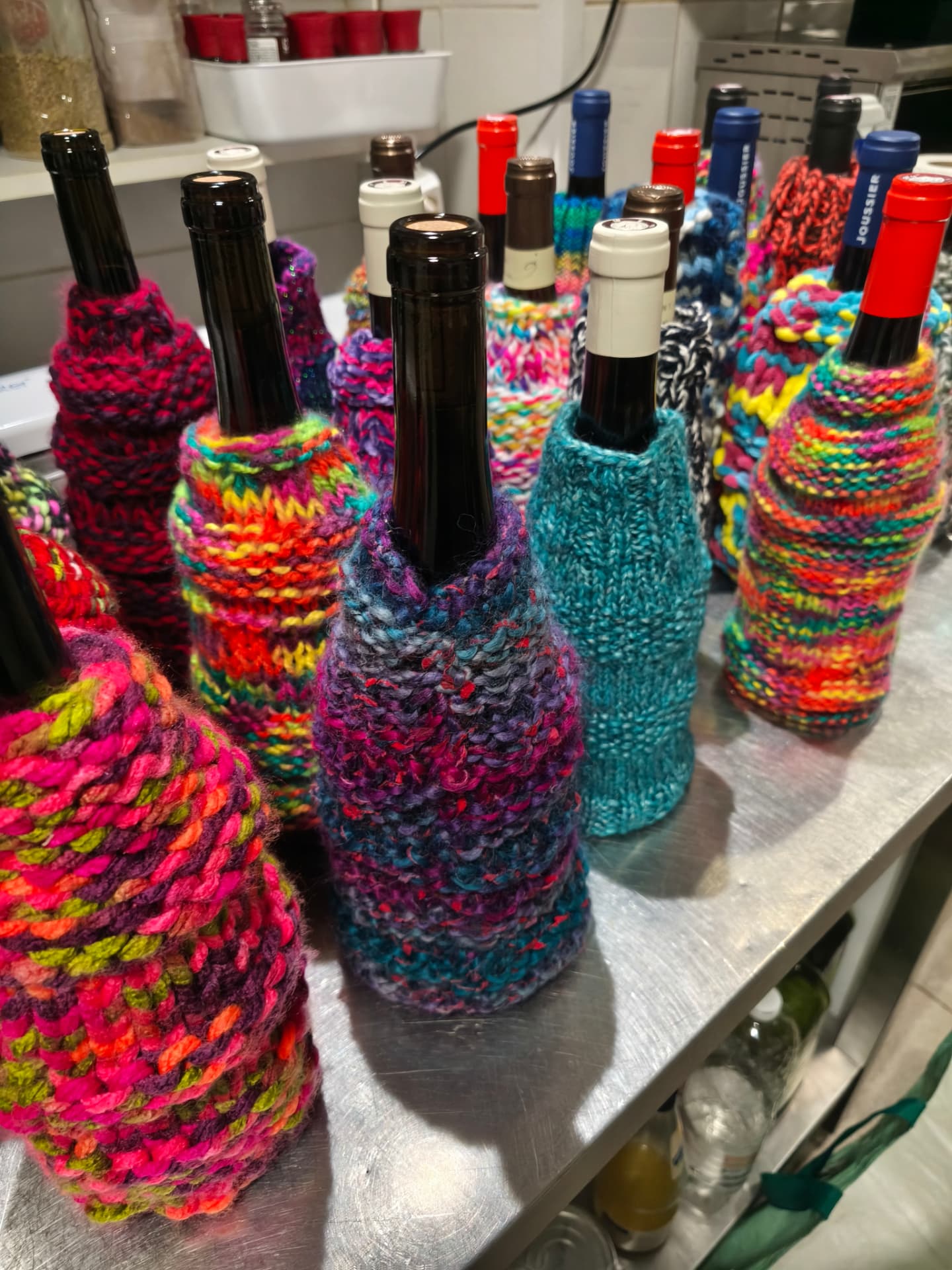 Trois bouteilles habillées de chaussettes tricotées à la main, très colorées