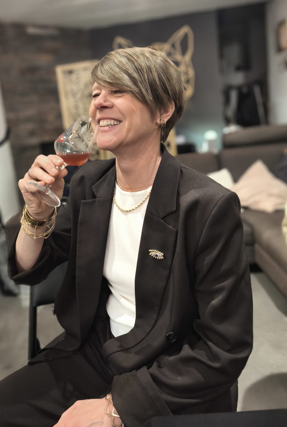 Véro, souriante, un verre de vin rosé à la main